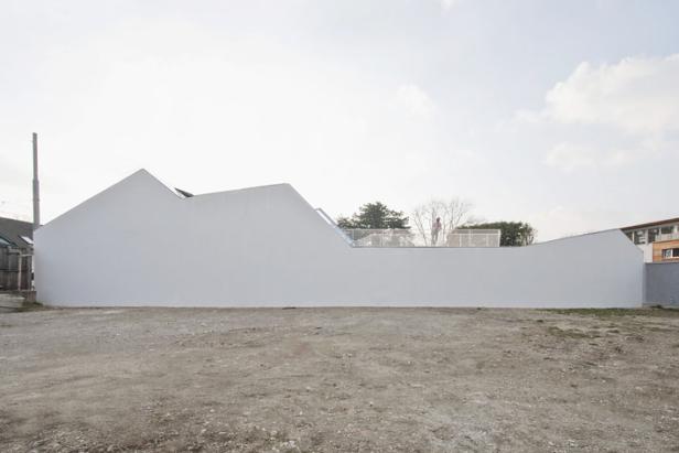 Ein weißes, modernes Haus mit einer Person auf der Dachterrasse.