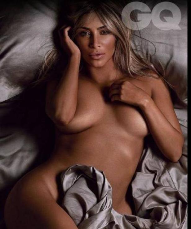 Kim Kardashian liegt auf einem Bett mit grauer Seide für ein GQ-Fotoshooting.