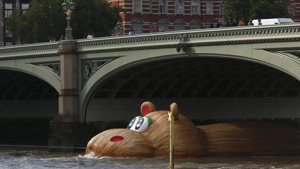 Ein hölzernes Nilpferd schwimmt unter einer Brücke auf der Themse in London.