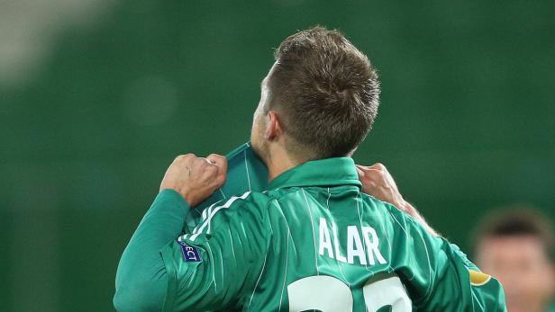 Ein Fußballspieler mit dem Namen „Alar“ auf dem Rücken zieht sein Trikot hoch.