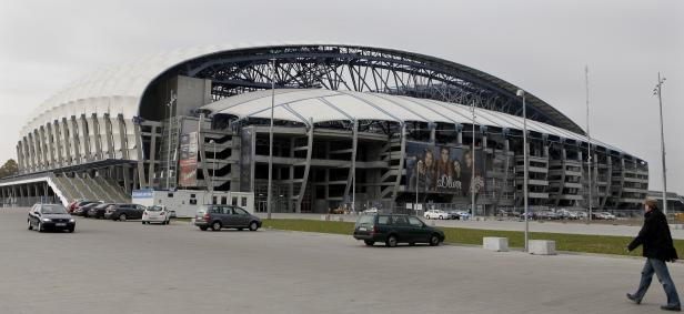 Das EM-Stadion in Posen Das Stadion Breslau mit Parkplatz und einem Fußgänger im Vordergrund.