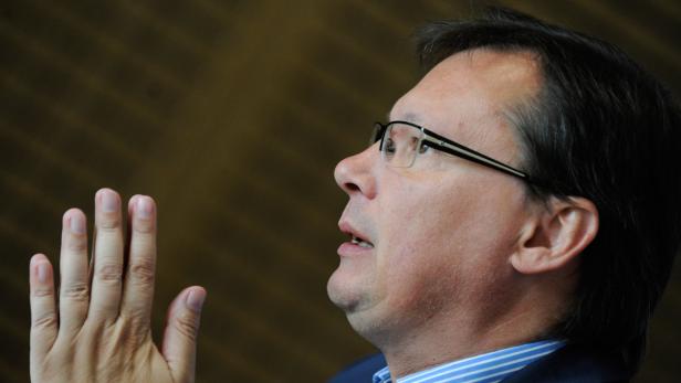 Ein Mann mit Brille gestikuliert mit der Hand.