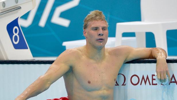 Ein erschöpfter Schwimmer ruht sich am Beckenrand aus.