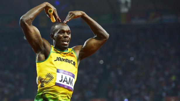 Usain Bolt jubelt mit einem Staffelholz in der Hand und formt mit seinen Händen ein Herz.