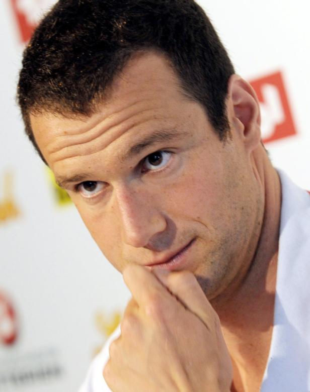 Ein Mann blickt nachdenklich mit der Hand am Kinn zur Seite.