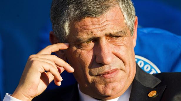 Ein Mann in einem Anzug blickt nachdenklich mit der Hand am Kopf.