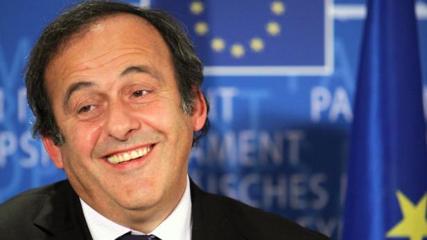 Michel Platini lächelt vor einer Europafahne.