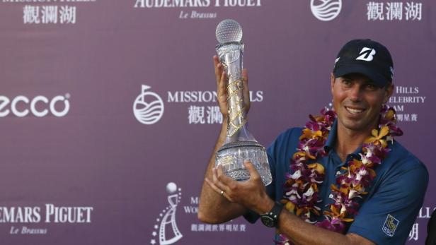Ein Golfspieler mit Blumenkette hält eine Trophäe in die Höhe.