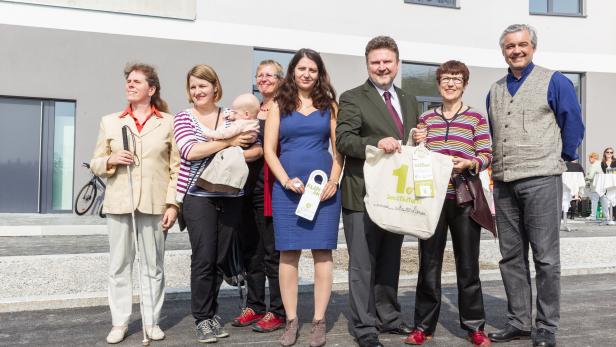 Eine Gruppe von Personen posiert vor einem Gebäude, darunter eine Frau mit Blindenstock.