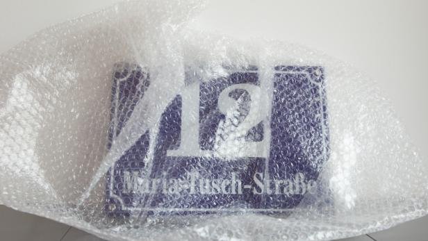 Ein Straßenschild mit der Aufschrift „Maria-Tusch-Straße 12“ ist in Luftpolsterfolie verpackt.