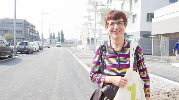 Eine lächelnde Frau mit Brille steht auf einer neu gebauten Straße.