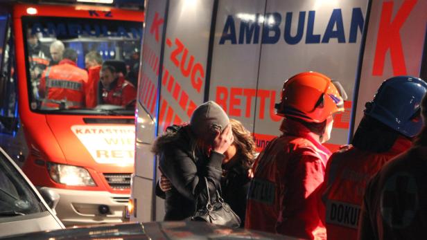 Eine Frau weint vor einem Rettungswagen, umgeben von Sanitätern.
