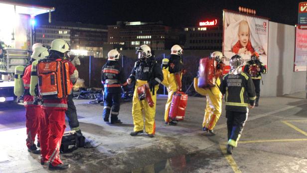 Eine Gruppe Feuerwehrleute steht nachts vor einem Gebäude.