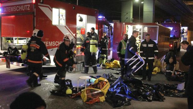 Mehrere Feuerwehrleute stehen vor ihren Einsatzfahrzeugen und bereiten sich vor.