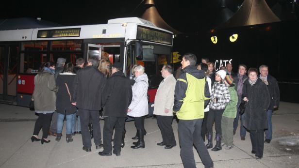 Eine Gruppe von Menschen steigt in einen Bus vor dem Musical „Cats“.