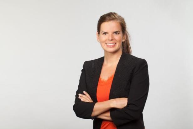 Eine Frau mit verschränkten Armen lächelt in die Kamera.