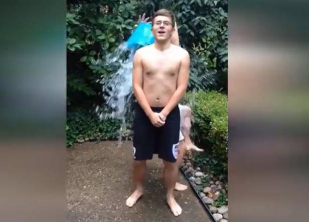 Ein junger Mann wird mit einem Eimer Wasser übergossen.