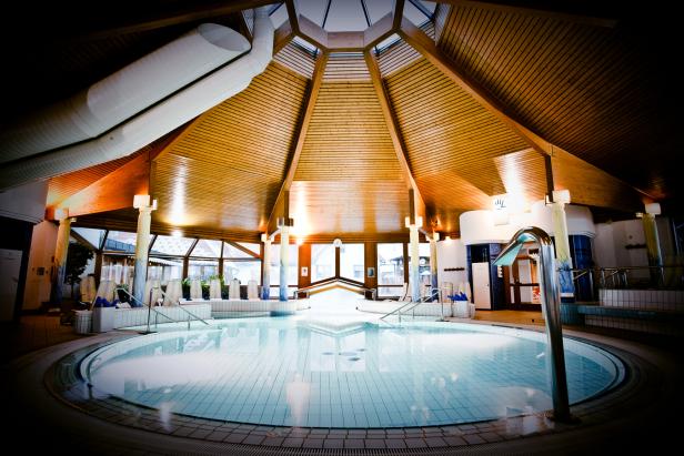 Ein Innenpool mit einem hölzernen Kuppeldach und großen Fenstern.