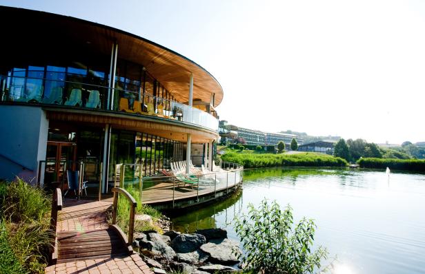 Ein modernes Gebäude mit Terrasse am Ufer eines Sees.