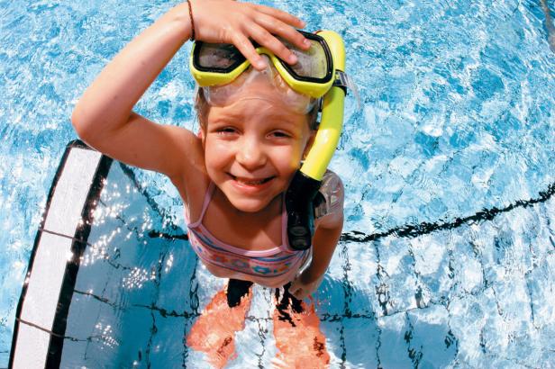 Ein Mädchen mit Schnorchel und Schwimmflossen im Schwimmbad.