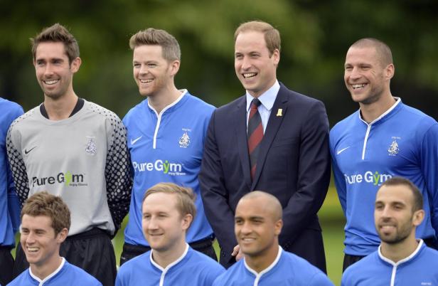 Prinz William posiert mit einer Fußballmannschaft für ein Gruppenfoto.