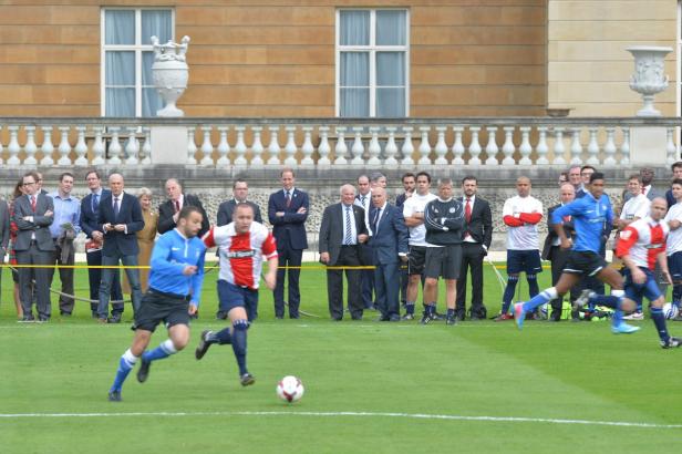 Fußballspieler spielen vor den Augen von Prinz William ein Fußballspiel.