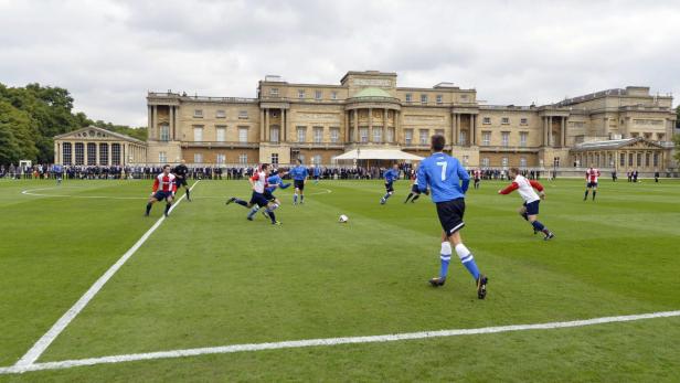 Fußballspieler spielen vor dem Buckingham Palace Fußball.