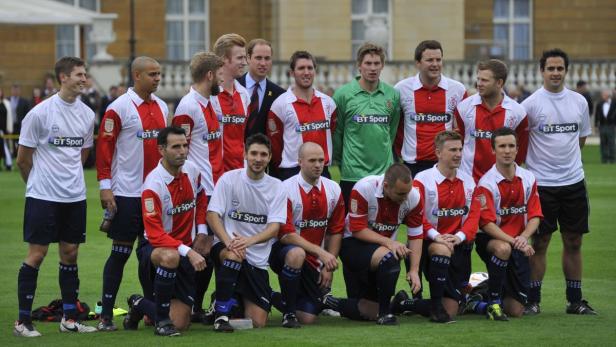 Eine Gruppe von Fußballspielern posiert für ein Mannschaftsfoto vor einem Gebäude.