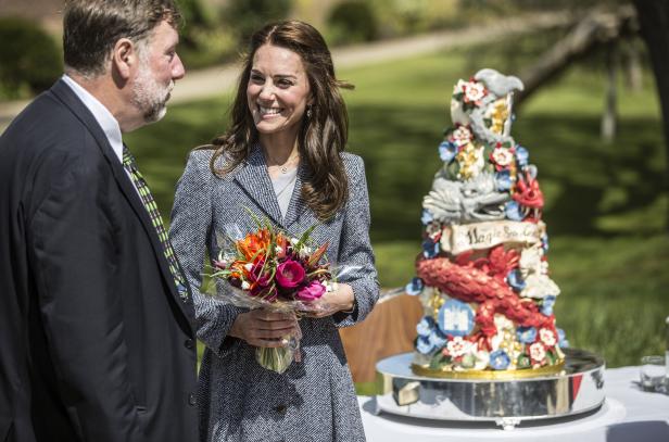 Catherine, Prinzessin von Wales, hält einen Blumenstrauß neben einer verzierten Statue.