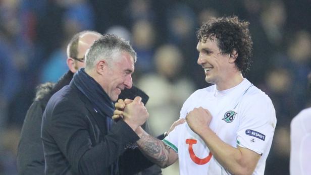Ein Trainer und ein Fußballspieler von Hannover 96 schütteln sich die Hände.