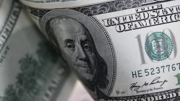 Nahaufnahme eines gerollten 100-Dollar-Scheins mit dem Porträt von Benjamin Franklin.