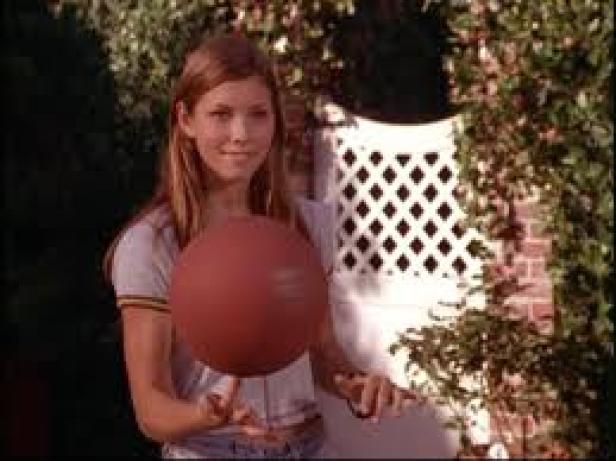 Eine junge Frau balanciert einen Basketball auf ihrem Finger.