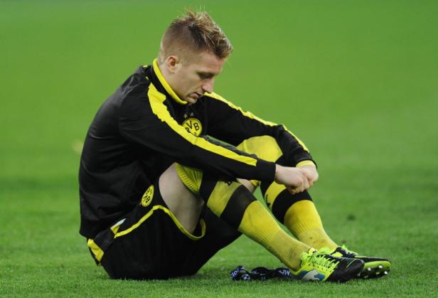 Ein Fußballspieler von Borussia Dortmund sitzt niedergeschlagen auf dem Rasen.