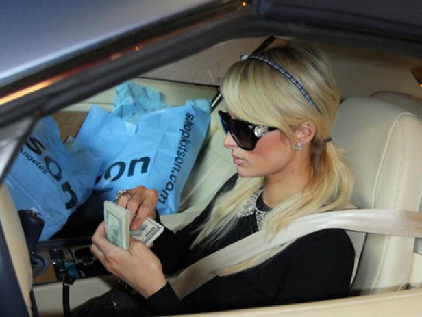 Paris Hilton sitzt im Auto und zählt Geldscheine.