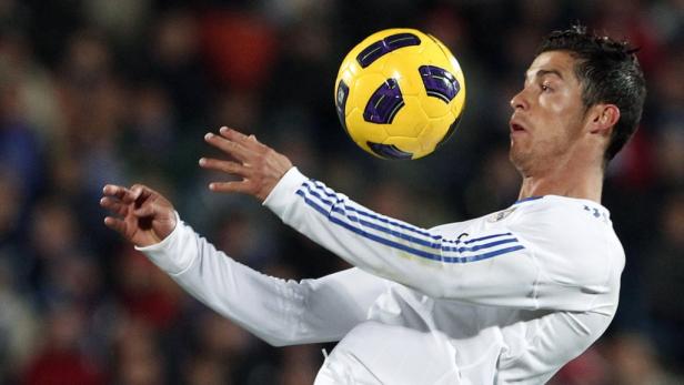 Cristiano Ronaldo köpft einen gelben Fußball.