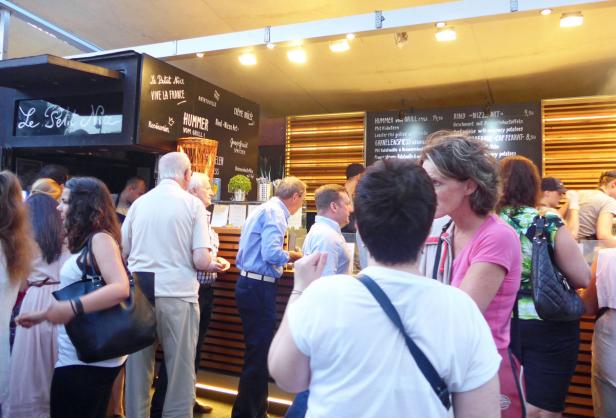 Menschen stehen vor einem Imbissstand mit dem Namen „Le Petit Nice“.