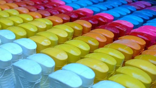 Viele bunte Sprühflaschen stehen in Reihen nebeneinander.