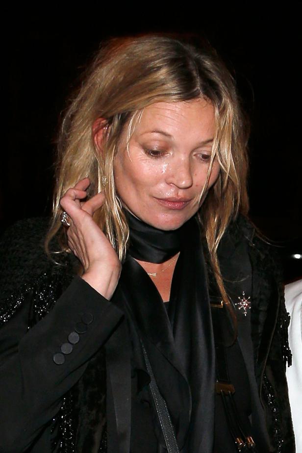Kate Moss trägt einen schwarzen Blazer und blickt nach unten.