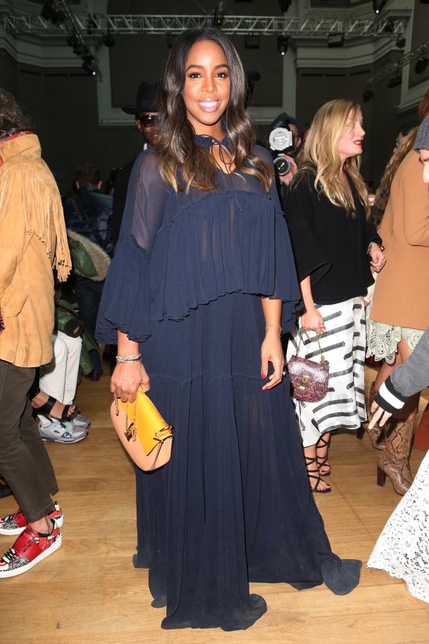Kelly Rowland trägt ein langes, blaues Kleid und eine gelbe Handtasche bei einer Veranstaltung.