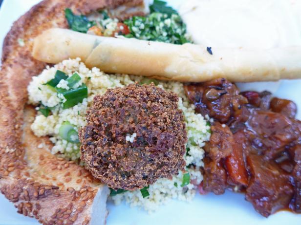 Ein Teller mit Falafel, Couscous, einer Frühlingsrolle und Gemüse.