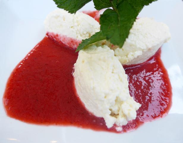 Drei Nocken Quark liegen auf Erdbeersoße und sind mit Minze garniert.