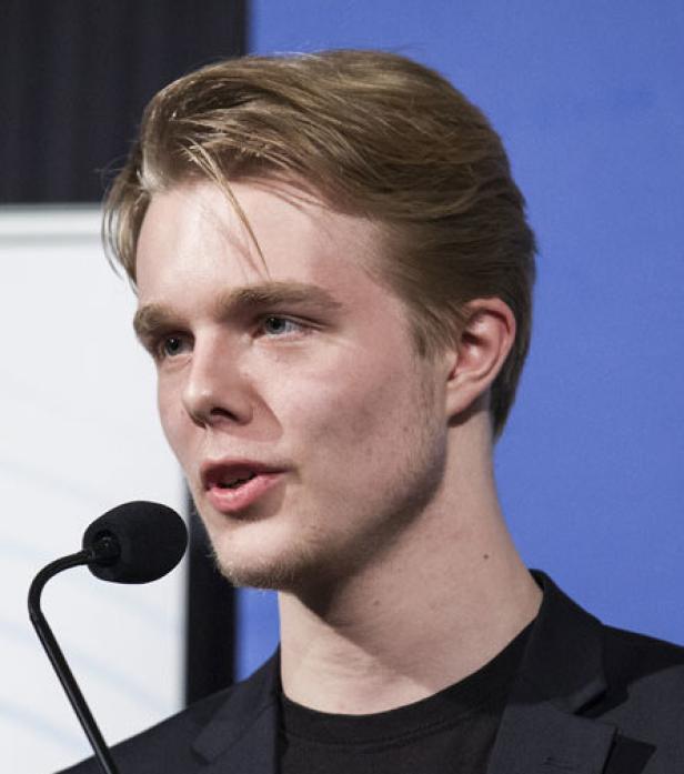 Ein junger Mann spricht vor einem Mikrofon.