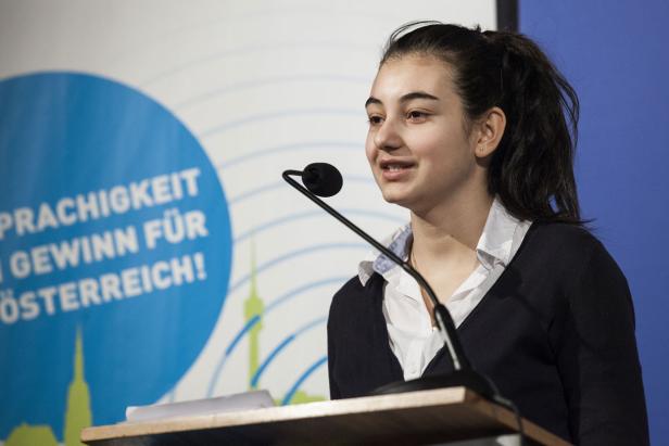 Eine junge Frau spricht bei einer Veranstaltung am Rednerpult.