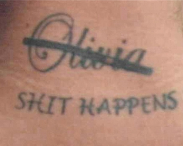 Ein Tattoo mit dem durchgestrichenen Namen „Olivia“ und dem Schriftzug „Shit Happens“.