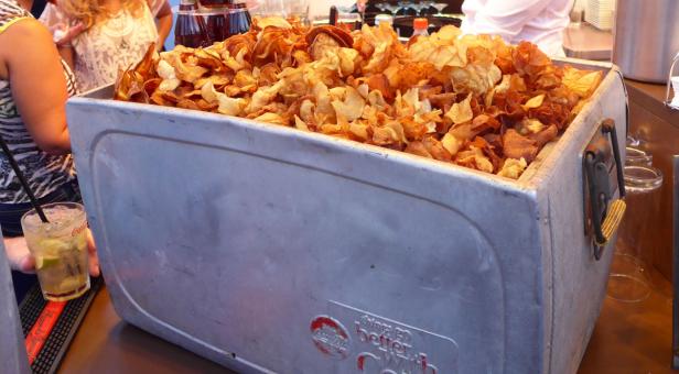 Ein Behälter voll mit hausgemachten Kartoffelchips steht auf einer Theke.