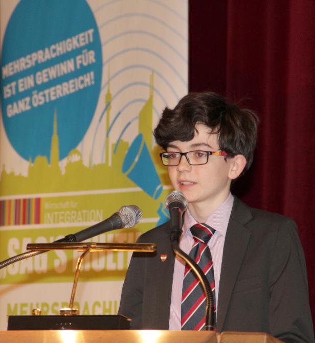 Ein junger Mann hält eine Rede auf einer Veranstaltung zum Thema Mehrsprachigkeit.