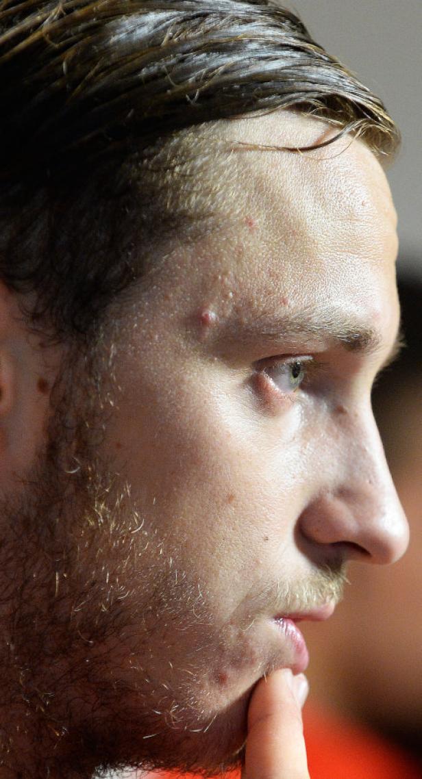 Ein Mann mit Bart berührt nachdenklich sein Kinn.