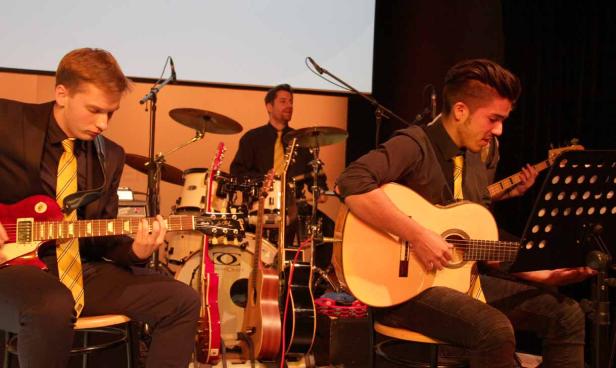Eine Band spielt live auf der Bühne mit Gitarren, Bass und Schlagzeug.