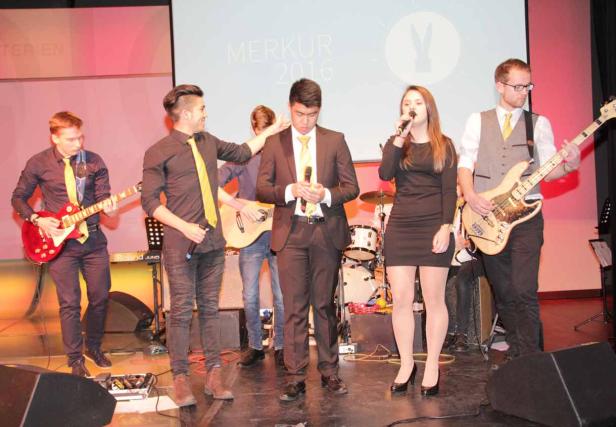 Eine Band tritt auf einer Bühne vor einem Publikum auf.