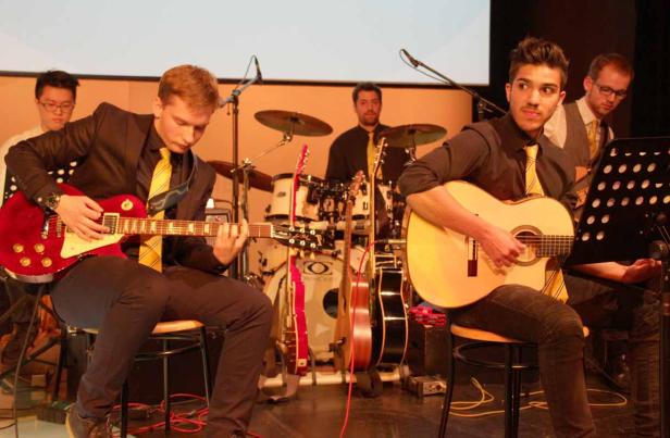 Eine Band spielt auf der Bühne mit Gitarren und Schlagzeug.